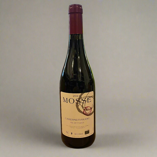 Bottle of Mosse Cabernet Franc wine on a wooden table with a store interior in the background.