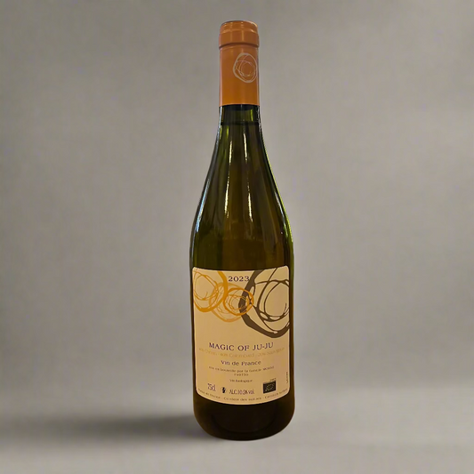 Bottle of 'Magic of JuJu' wine on a wooden table with a store interior in the background.